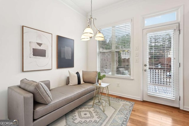 living room with an inviting chandelier, ornamental molding, and light wood-type flooring