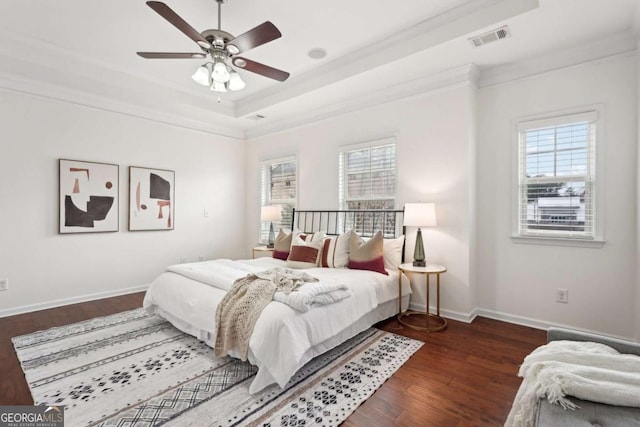 bedroom featuring a raised ceiling, ornamental molding, dark wood-type flooring, and ceiling fan