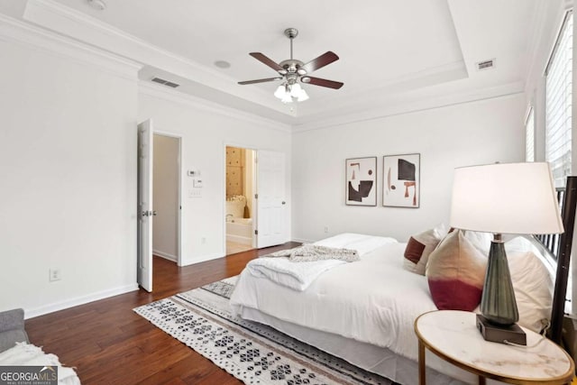 bedroom featuring crown molding, connected bathroom, dark hardwood / wood-style floors, and a raised ceiling