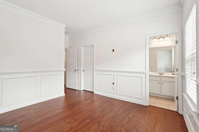 unfurnished bedroom featuring dark wood-type flooring, ornamental molding, and ensuite bathroom