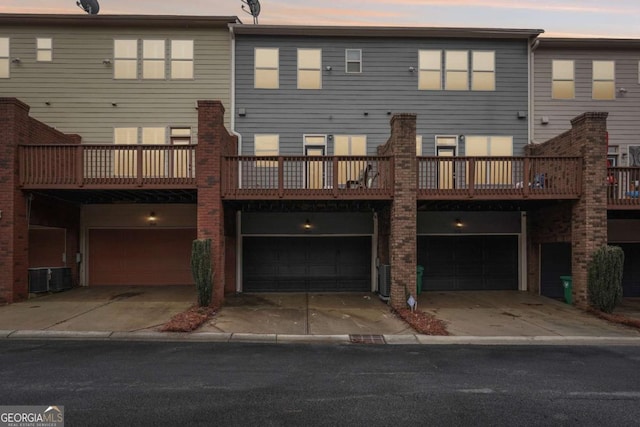 back house at dusk featuring a garage and a balcony