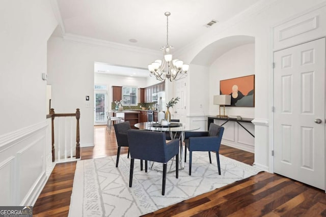 dining area featuring ornamental molding, hardwood / wood-style floors, and a notable chandelier