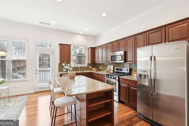 kitchen with ornamental molding, stainless steel appliances, and a kitchen island