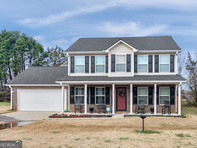 view of front of home featuring a garage, a front yard, and covered porch