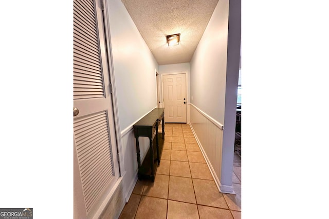 hall featuring light tile patterned flooring and a textured ceiling