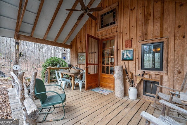 interior space featuring ceiling fan, vaulted ceiling with beams, and an outdoor fireplace