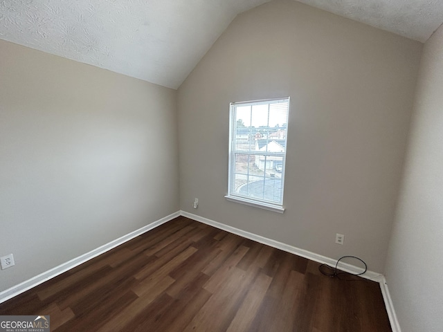 interior space with dark hardwood / wood-style flooring, vaulted ceiling, and a textured ceiling