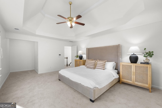 bedroom with ceiling fan, light colored carpet, and a raised ceiling