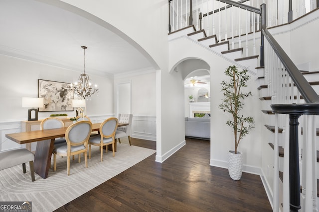 dining space with stairs, arched walkways, wood finished floors, and crown molding