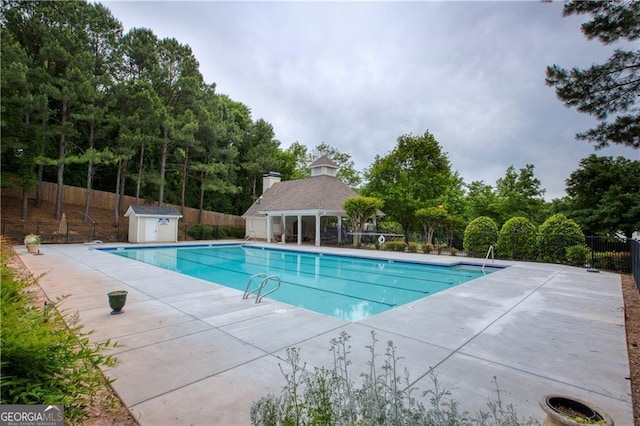 view of swimming pool featuring a shed and a patio area