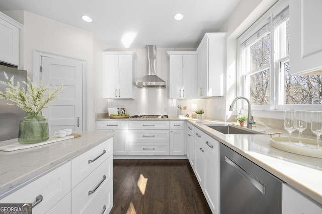 kitchen with white cabinetry, wall chimney range hood, sink, and appliances with stainless steel finishes