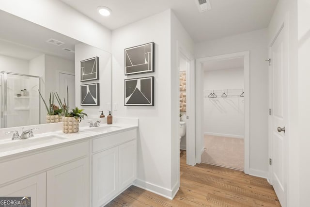 bathroom with vanity, toilet, a shower with shower door, and wood-type flooring