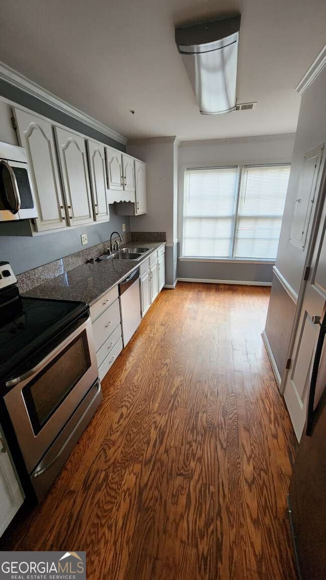 kitchen with appliances with stainless steel finishes, sink, white cabinets, and dark stone counters