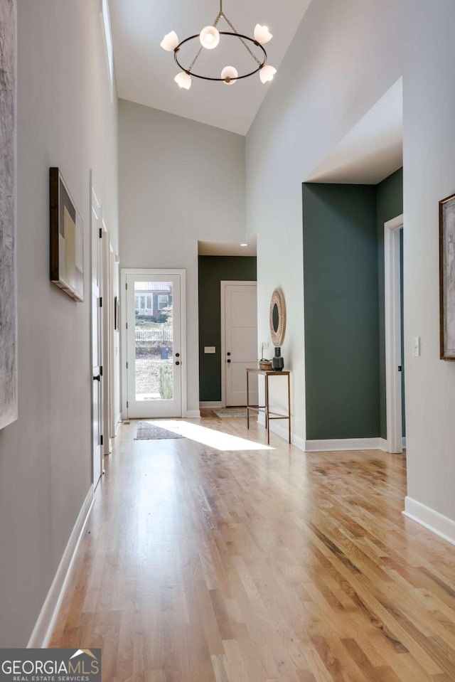 entryway featuring a towering ceiling, a chandelier, and light hardwood / wood-style floors