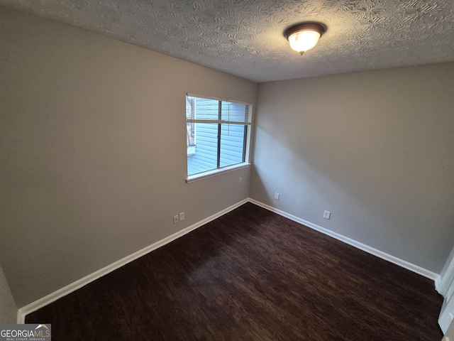 unfurnished room featuring dark hardwood / wood-style flooring and a textured ceiling