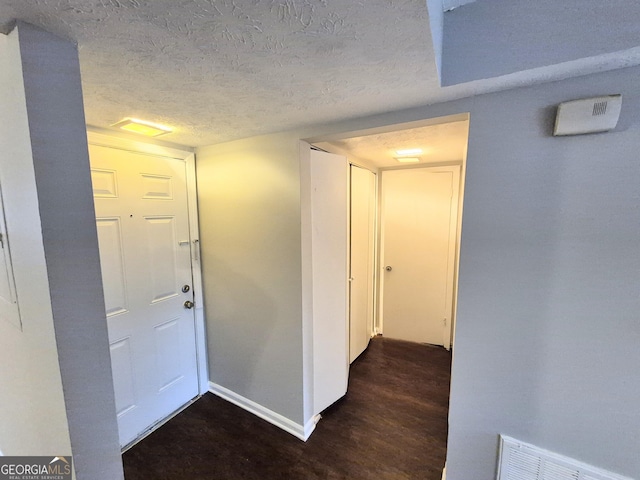 hallway with dark wood-type flooring and a textured ceiling