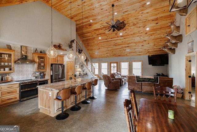 kitchen featuring pendant lighting, high vaulted ceiling, a breakfast bar area, stainless steel appliances, and light stone countertops