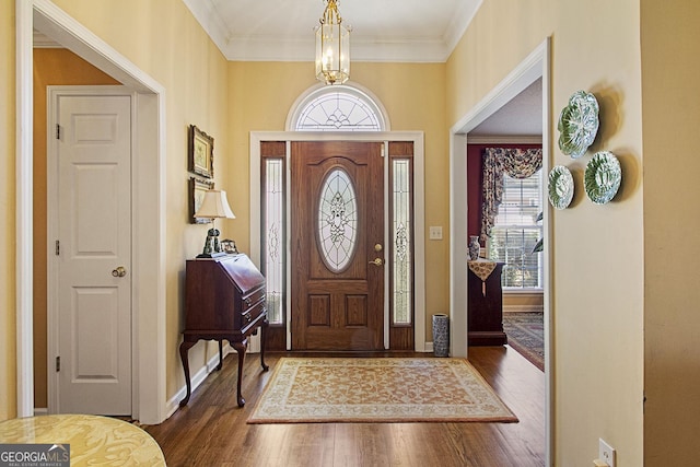 foyer entrance with an inviting chandelier, ornamental molding, and dark hardwood / wood-style floors