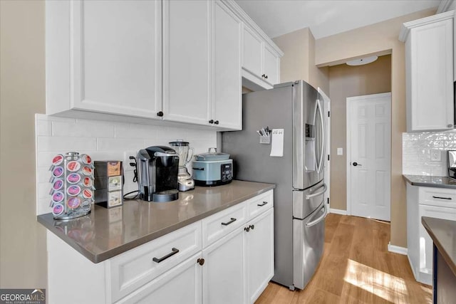 kitchen featuring tasteful backsplash, stainless steel fridge, white cabinets, and light wood-type flooring