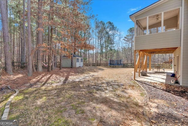 view of yard featuring a trampoline, a storage shed, and a patio area