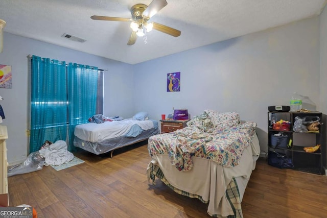bedroom featuring a textured ceiling, wood-type flooring, and ceiling fan