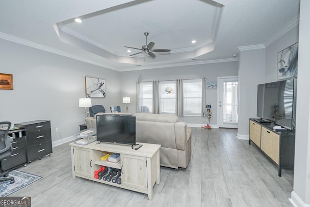 living room with a tray ceiling, ceiling fan, and light wood-type flooring