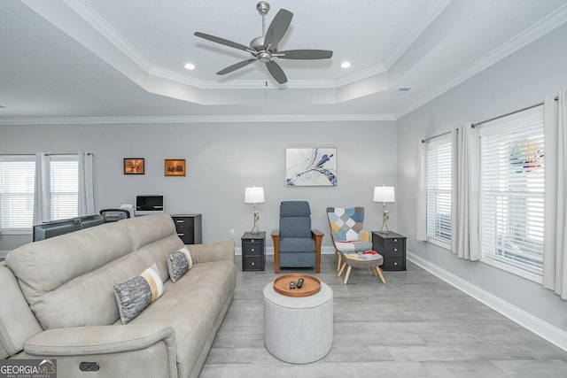 living room with crown molding, a tray ceiling, and plenty of natural light