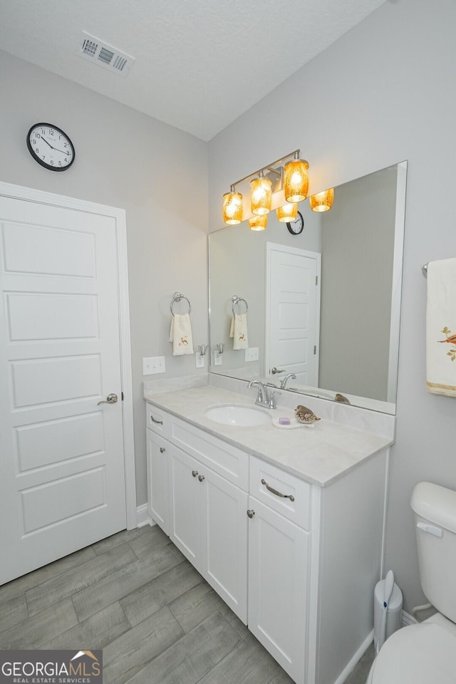 bathroom with vanity, hardwood / wood-style floors, and toilet