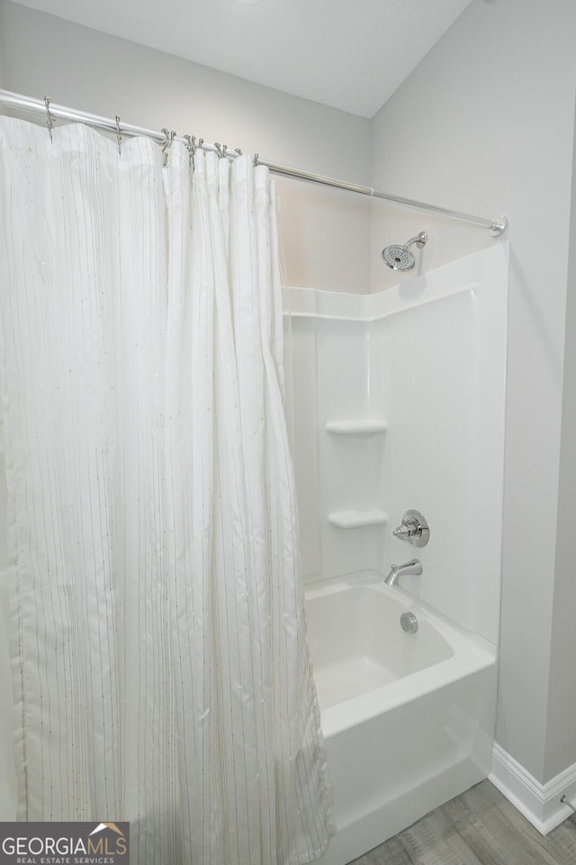 bathroom featuring wood-type flooring and shower / bath combo with shower curtain