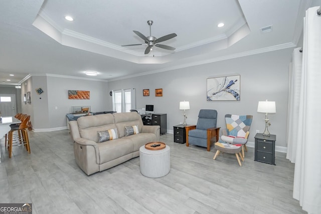 living room featuring crown molding, light hardwood / wood-style floors, a raised ceiling, and ceiling fan