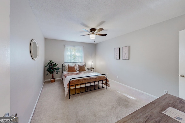 bedroom with ceiling fan, light carpet, and a textured ceiling