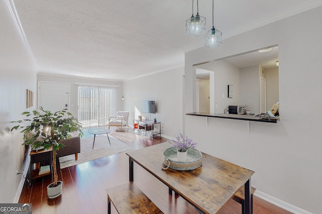 dining area featuring crown molding, wood-type flooring, and a textured ceiling