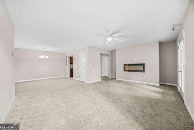 unfurnished living room featuring ceiling fan with notable chandelier and light colored carpet