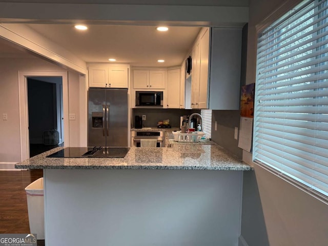 kitchen featuring kitchen peninsula, white cabinetry, light stone countertops, and black appliances