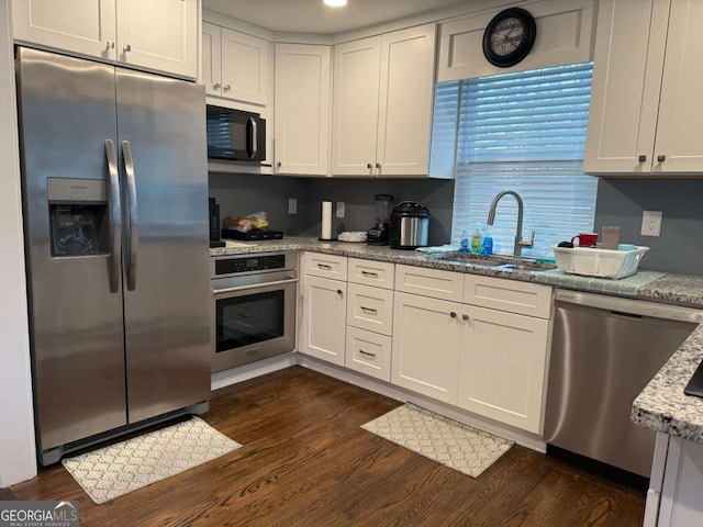 kitchen with appliances with stainless steel finishes, sink, light stone counters, and white cabinets