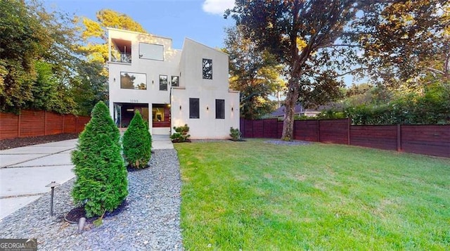 contemporary home featuring a front yard, a fenced backyard, and stucco siding