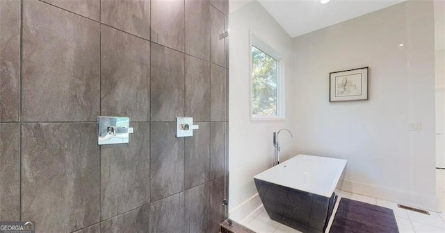 full bath with baseboards, tiled shower, and tile patterned flooring