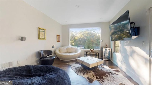 living area featuring wood finished floors, visible vents, and baseboards