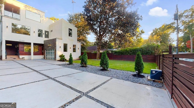 exterior space with a lawn, concrete driveway, fence private yard, and stucco siding