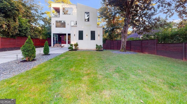 back of house featuring a lawn, a fenced backyard, and stucco siding