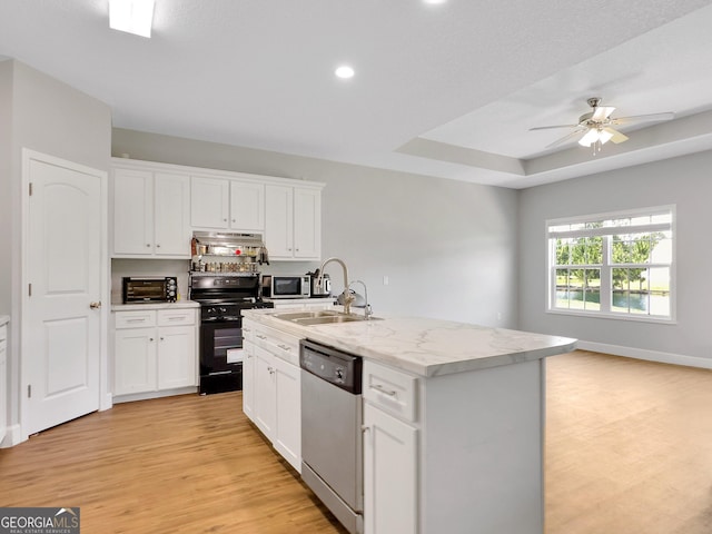 kitchen featuring a center island with sink, appliances with stainless steel finishes, sink, white cabinetry, and a tray ceiling