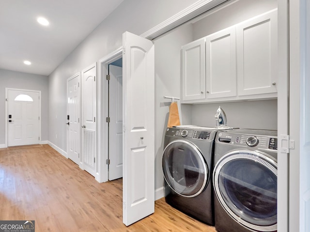 washroom with light hardwood / wood-style floors, washer and clothes dryer, and cabinets