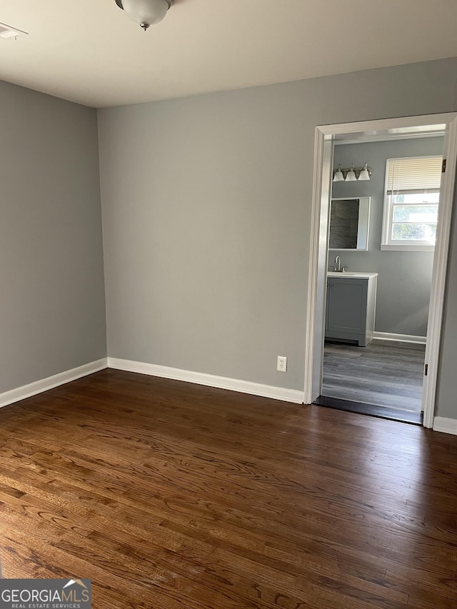 spare room with dark wood-type flooring and sink