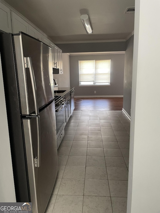 kitchen with white cabinetry, sink, light tile patterned floors, stainless steel appliances, and crown molding