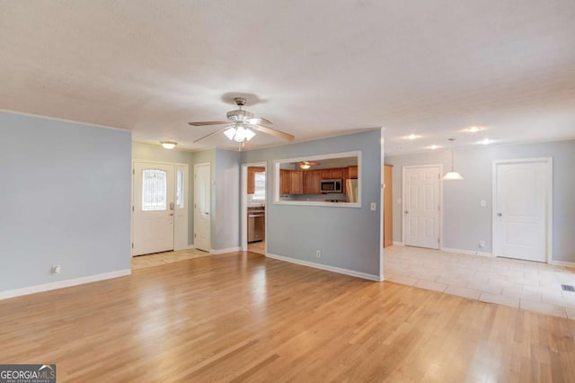 unfurnished living room with light wood-style floors, visible vents, baseboards, and a ceiling fan