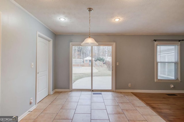 unfurnished dining area with a textured ceiling, crown molding, visible vents, and baseboards