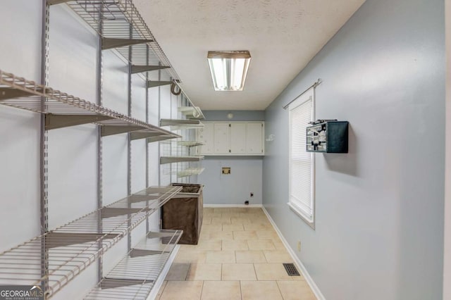 laundry room featuring a textured ceiling, washer hookup, baseboards, cabinet space, and electric dryer hookup