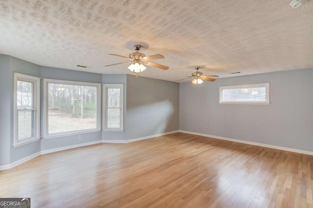 unfurnished room featuring a textured ceiling, light wood-type flooring, and baseboards