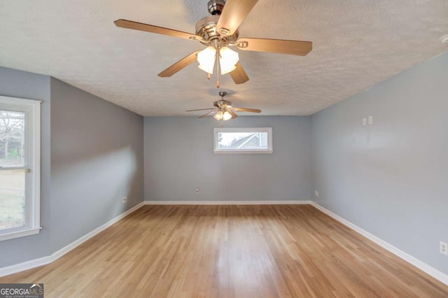 unfurnished room featuring a textured ceiling, baseboards, and wood finished floors