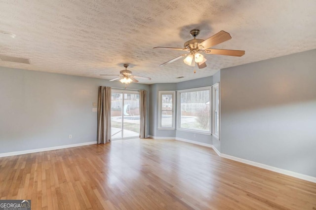 unfurnished room featuring light wood finished floors, visible vents, ceiling fan, a textured ceiling, and baseboards